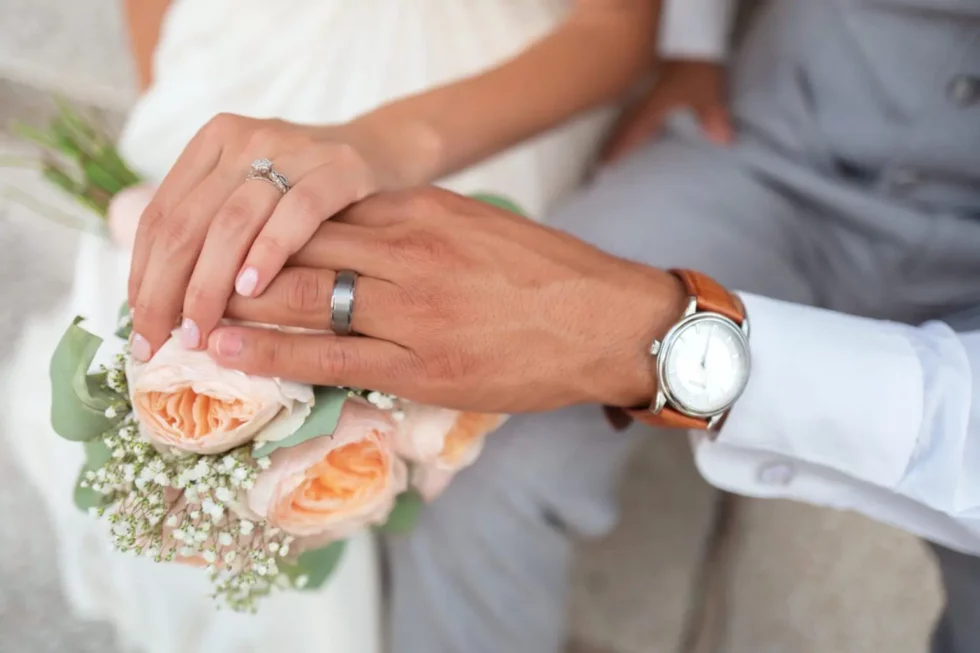 The hands of a recently married couple holding the wedding boquete